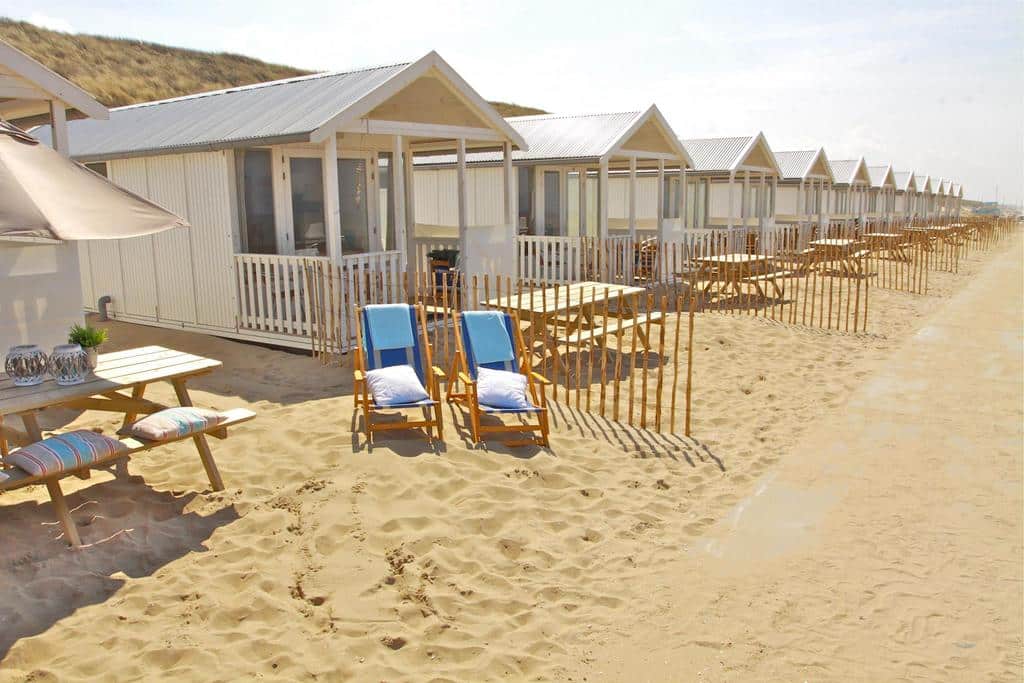 Vue extérieure des cabanons avec morceau de plage privative et table dans le sable