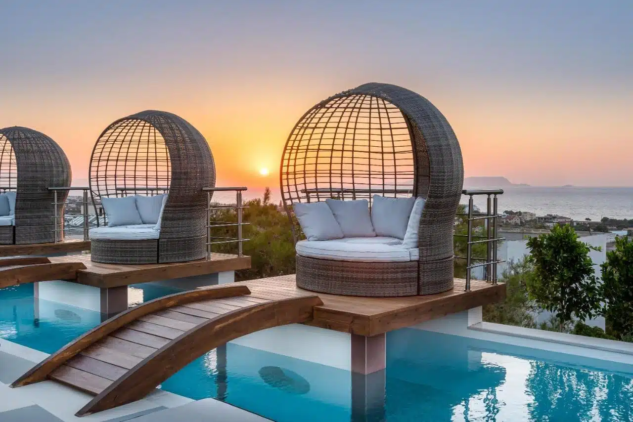 transat double design sur ponton au dessus de la piscine au coucher du soleil en grèce