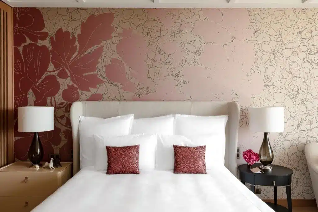 Papier peint dans les teintes roses et tête de lit beige pour cette chambre d'hôtel de luxe