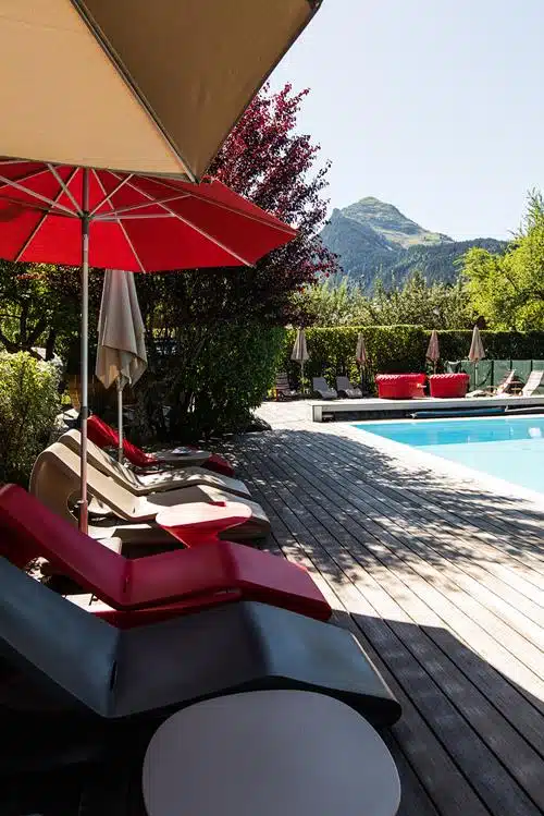 piscine extérieure chauffée et transat dans un hôtel de montagne à Morzine