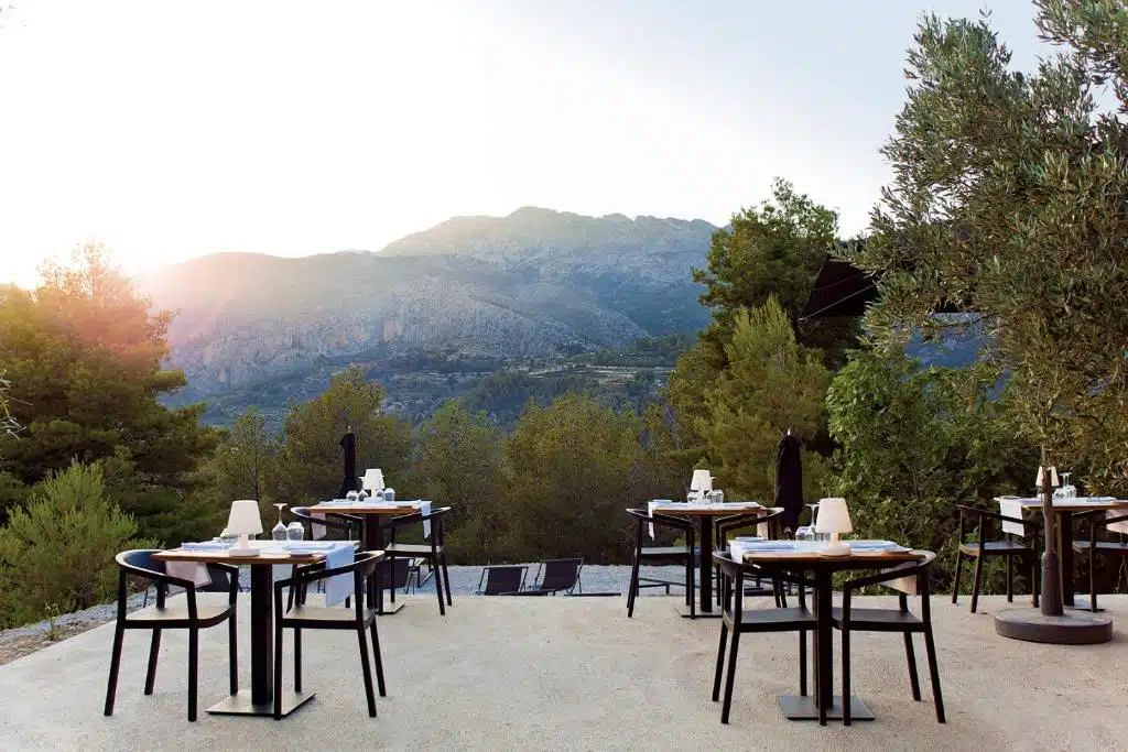 Terrasse du restaurant extérieur avec au fond la piscine de l'hôtel et la vue sur les montagnes