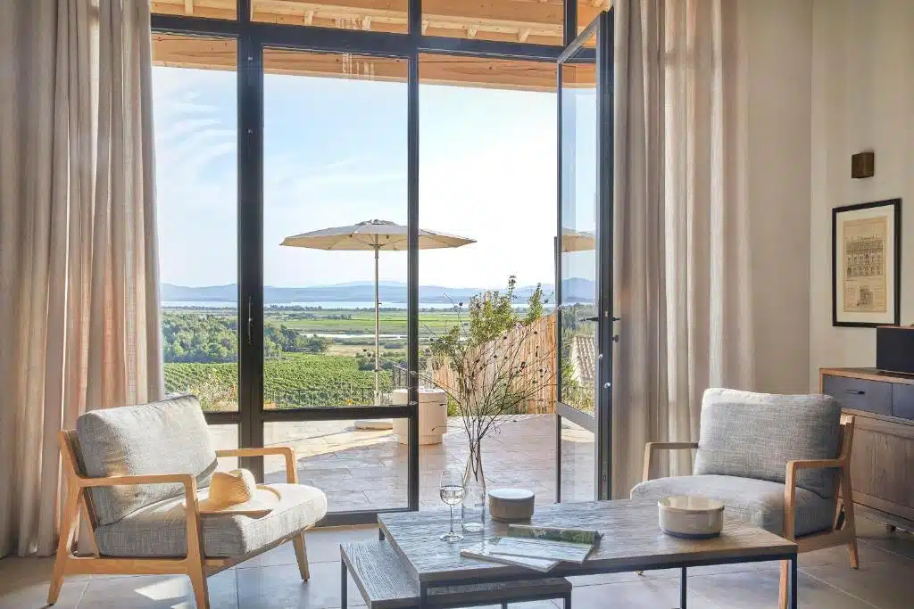 salon avec baie vitrée offrant une vue panoramique sur les étangs de l'Aude et les vignes du Languedoc-Roussillon