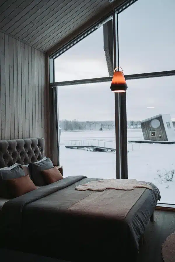 chambre avec baie vitrée panoramique permettant de contempler les aurores boréales depuis le lit en Laponie Suédoise