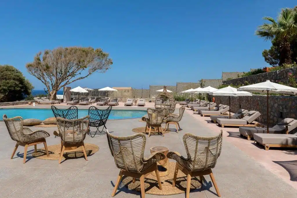 terrasse avec transat et salon de jardin au bord de la piscine extérieure de l'hôtel