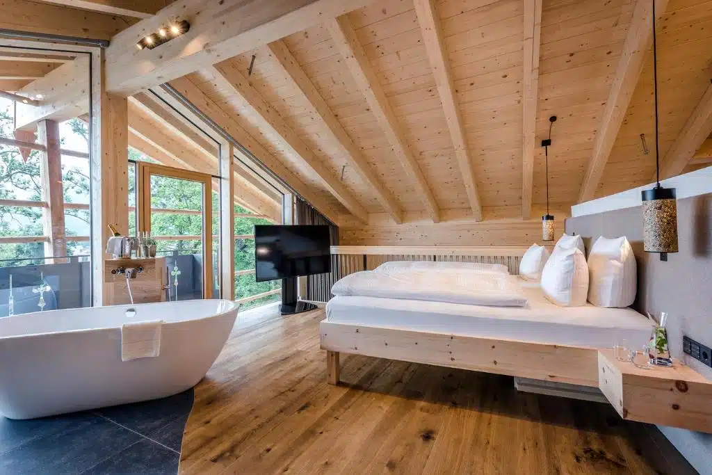 chambre avec baignoire ouverte sur la chambre et grande baie vitrée pour être en contact avec la nature