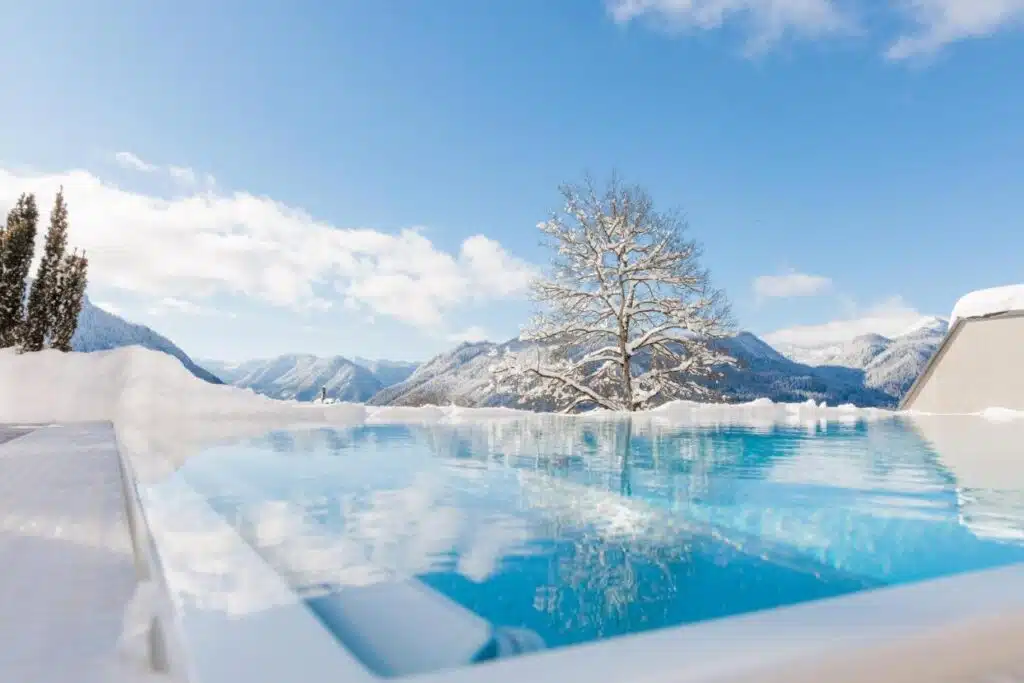 piscine extérieure chauffée de l'hôtel sous la neige et avec vue panoramique sur les montagnes d'Autriche